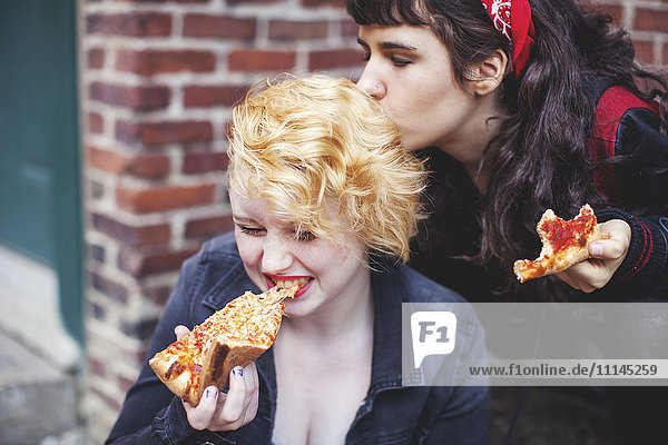 Caucasian women eating pizza outdoors