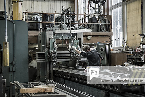 Kaukasischer Mann bei der Arbeit mit Maschinen in einer Metallwerkstatt