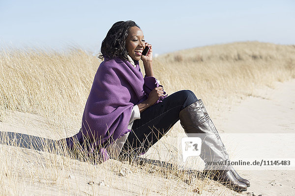 Frau spricht mit Handy am Strand