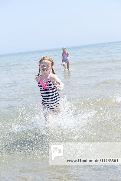 Kaukasisches Mädchen plantscht in den Wellen am Strand