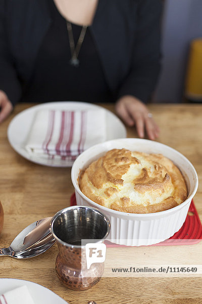 Girl sitting near baked souffle on table