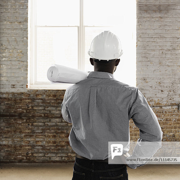 Black architect wearing hard-hat and holding blueprints