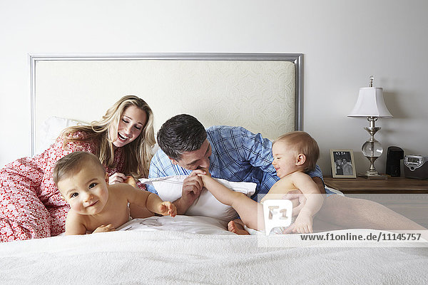 Caucasian family playing on bed