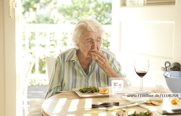 Ältere kaukasische Frau beim Mittagessen am Tisch