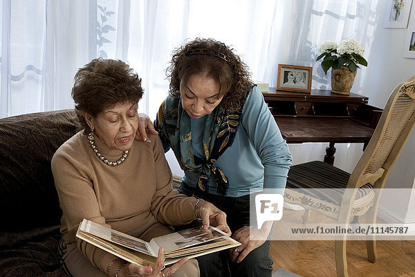 Hispanic mother and daughter looking at photo album