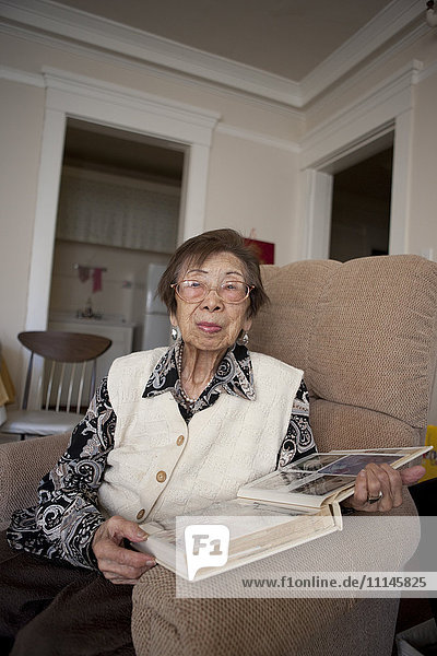 Ältere asiatische Frau schaut sich Fotoalbum an