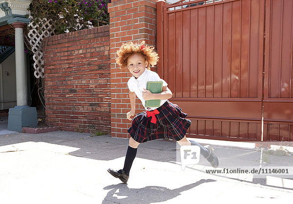 Smiling girl in school uniform running in driveway Smiling girl in school uniform running in driveway
