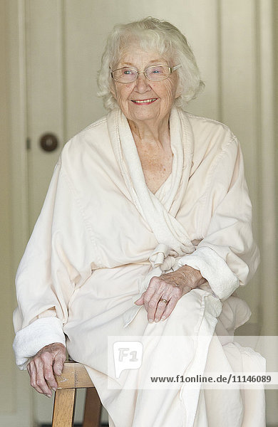 Older Caucasian woman sitting in bathrobe