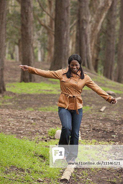 Black woman balancing on log in forest
