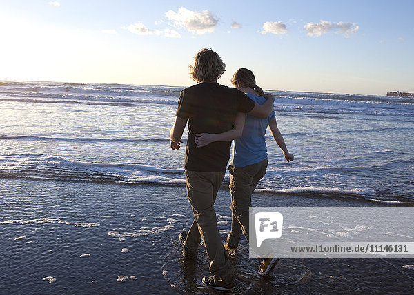 Couple hugging and walking in waves on beach