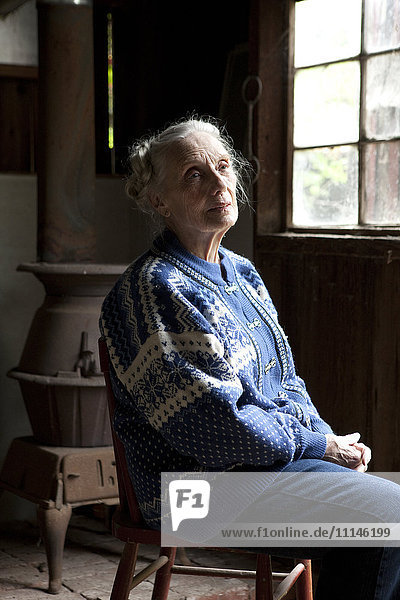 Ältere kaukasische Frau sitzt auf einem Stuhl