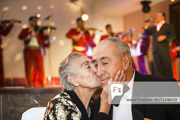 Hispanic couple kissing at wedding reception