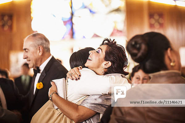 Hispanische Familie umarmt sich bei der Hochzeitsfeier