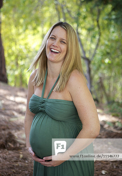 Laughing pregnant woman holding belly