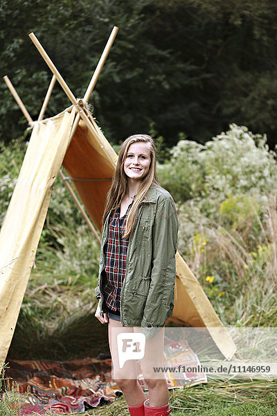 Lächelnde Frau vor einem Campingzelt
