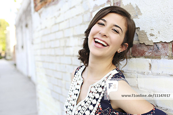 Smiling teenage girl leaning on brick wall