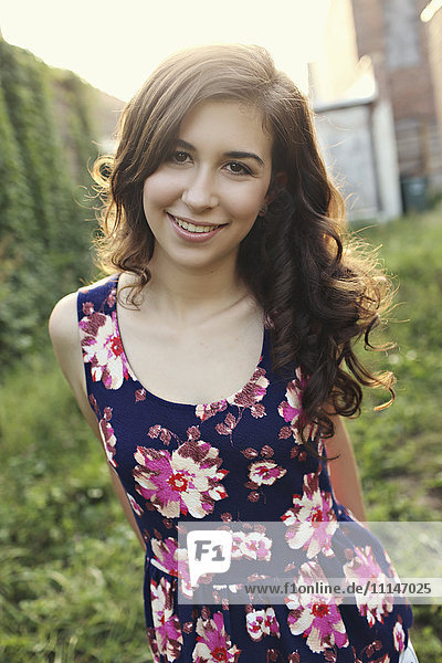 Smiling teenage girl standing in overgrown garden