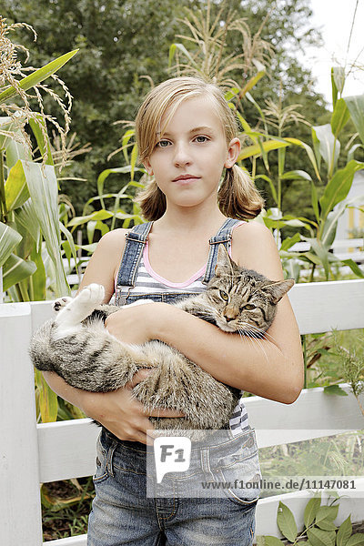 Seriöses Mädchen hält Katze im Garten