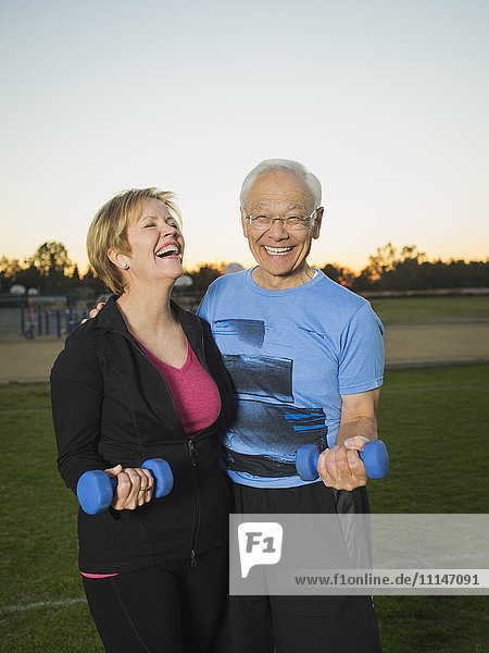 Älteres Paar hebt gemeinsam Gewichte im Stadtpark