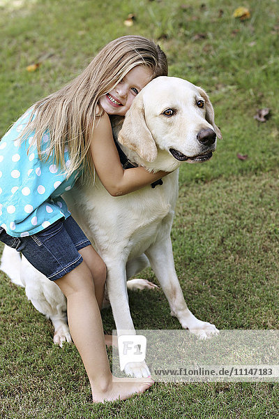 Smiling girl hugging dog in field