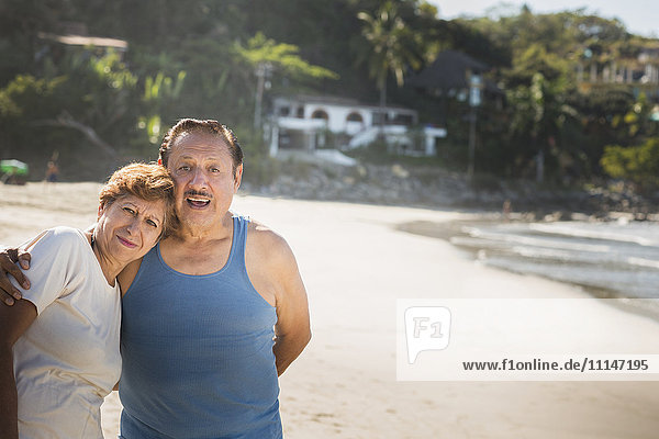Hispanisches Paar umarmt sich am Strand