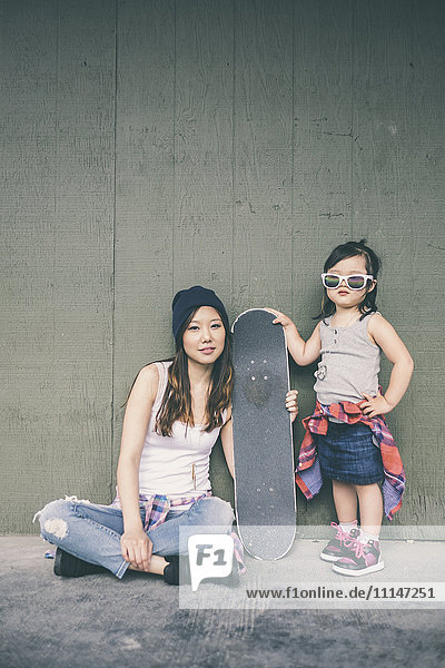 Koreanische Mutter und Tochter posieren mit Skateboard