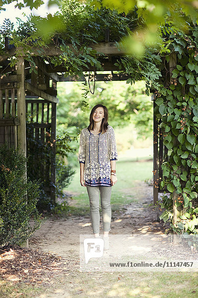 Girl standing under archway in garden