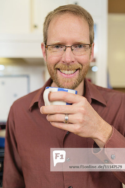 Caucasian man drinking cup of coffee in kitchen