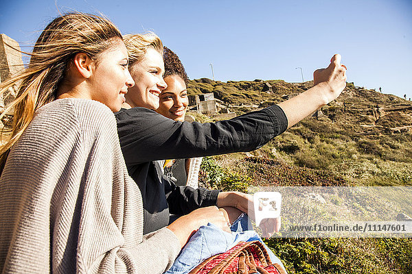 Frauen  die gemeinsam ein Handyfoto auf einem ländlichen Hügel machen