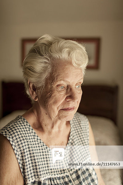 Pensive older woman sitting on bed