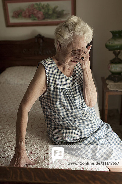 Traurige ältere Frau weint auf dem Bett