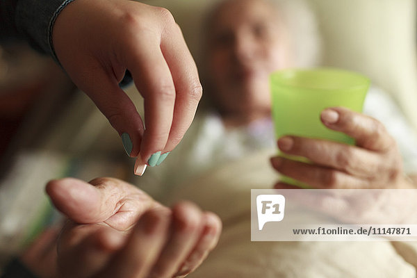 Enkelin gibt Großmutter Medikamente im Bett