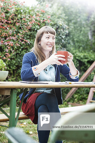 Mixed race businesswoman drinking coffee in backyard