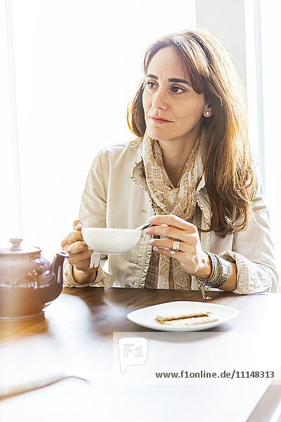 Kaukasische Frau trinkt Tee am Tisch