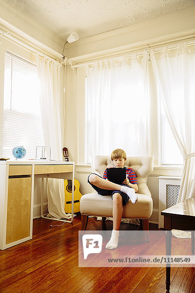 Kaukasischer Junge benutzt digitales Tablet im Wohnzimmer