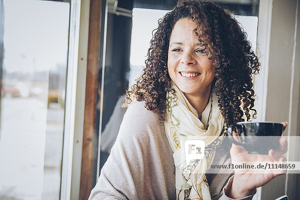 Mixed race woman drinking coffee in cafe