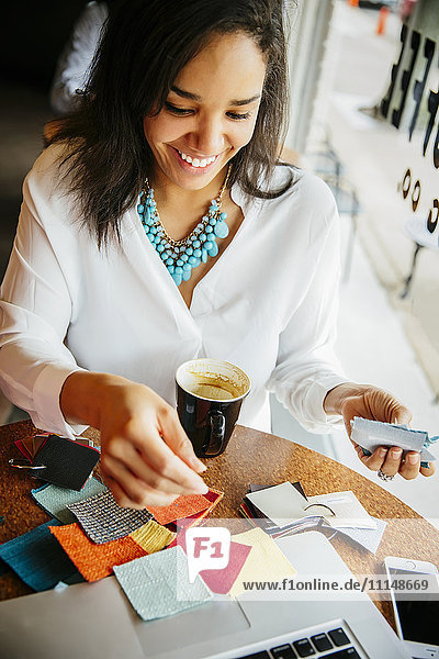 Geschäftsfrau begutachtet Stoffmuster in einem Cafe