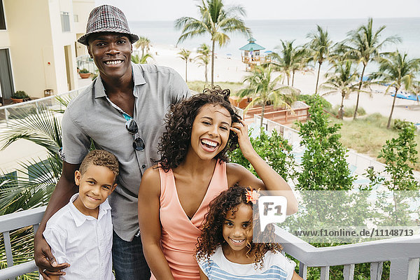 Familie lächelnd auf den Stufen mit Blick auf den Strand