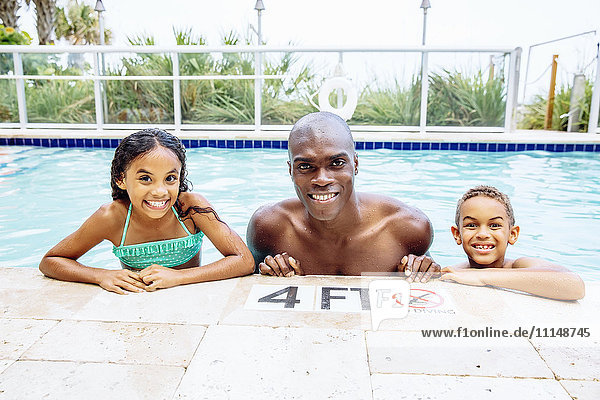 Vater und Kinder lächelnd im Schwimmbad