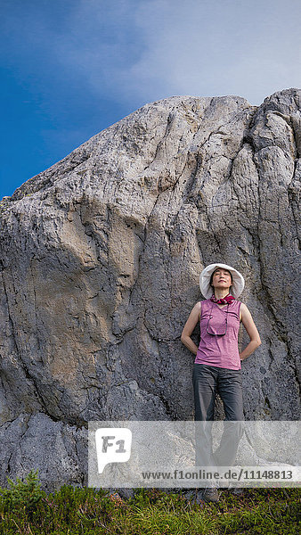 Japanische Frau lehnt sich an eine Felsformation