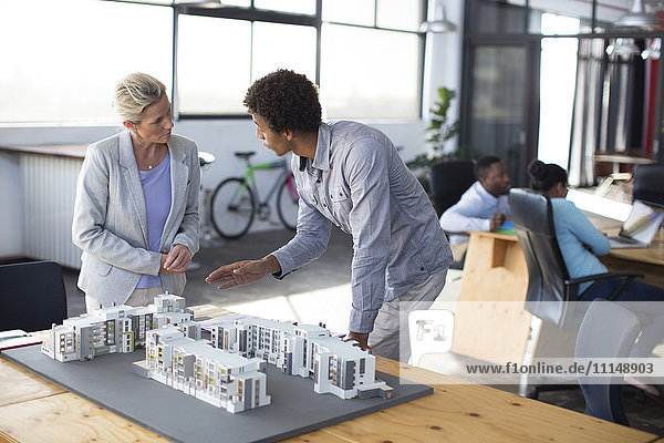 Architects examining architectural model in office