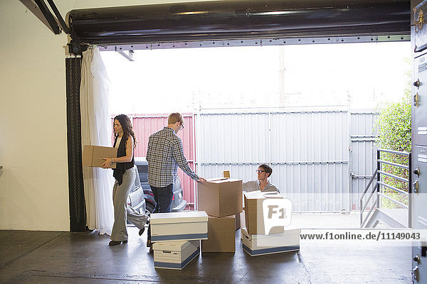 Kaukasische Geschäftsleute beim Auspacken von Kisten in einem neuen Büro