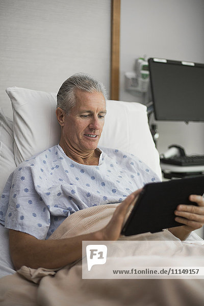 Kaukasischer Mann mit digitalem Tablet im Krankenhauszimmer