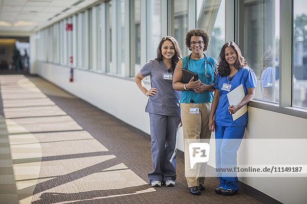 Nurses and doctor smiling in hospital hallway