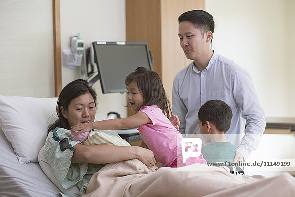 Family admiring newborn baby in hospital room