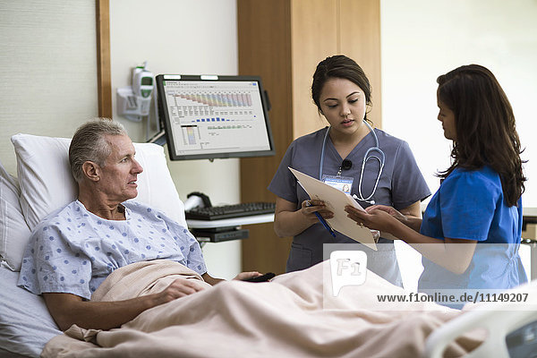 Krankenschwestern und Patienten unterhalten sich in einem Krankenhauszimmer