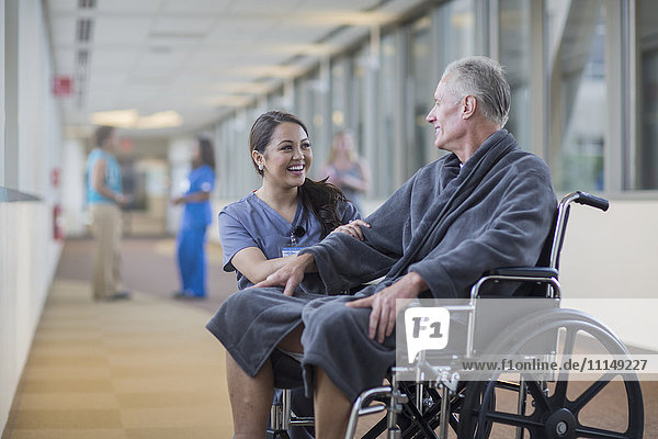 Krankenschwester spricht mit Patient im Rollstuhl
