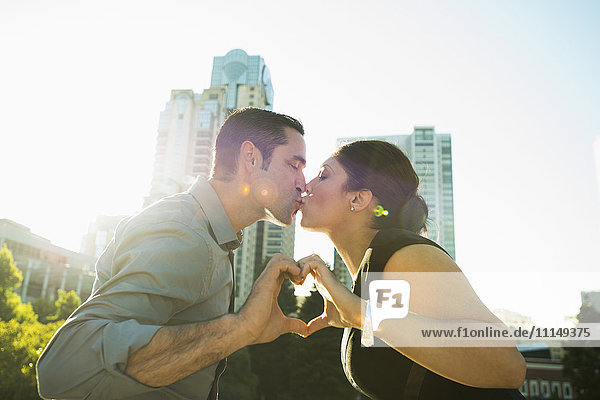 Hispanic Paar küssen und machen Herzform