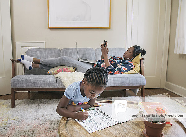 African American mother and daughter relaxing in living room
