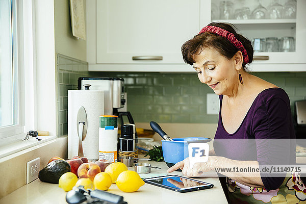 Kaukasische Frau benutzt digitales Tablet in der Küche